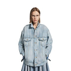 Person wearing a light blue denim jacket on a white background